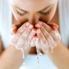 Frau reinigt ihr Gesicht, indem sie es wäscht