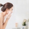 Frau reinigt ihr Gesicht zur Hautpflege am Morgen