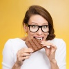 Frau mit Heißhunger beißt in Schokoladentafel