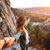 Horizont erweitern - junges Paar beim Wandern auf einem Berg, die Frau zeigt in Richtung Horizont.