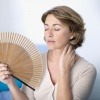 Eine Frau hält einen Fächer wegen der Hitzewallungen durch Hormone (Wechseljahre)