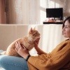 Frau liegt mit einer Katze auf einem Sofa