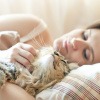 Frau kuschelt nach dem Aufwachen mit ihrer Katze im Bett.