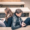 Keine Gemeinsamkeiten - Beziehung auf Abruf? Paar sitzt Rücken an Rücken auf dem Sofa, beide beschäftigen sich mit ihrem Smartphone.