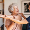 Im Pflegeberuf arbeitende Frau mit professioneller Kleidung hilft alter Frau