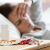 Eine Frau mit Krankheit liegt im Bett mit Tabletten daneben