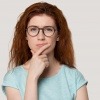 Junge dunkelhaarige Frau mit Brille in nachdenklicher Haltung