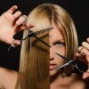 Eine Frau schneidet ihre langen Haare mit einer Schere mittellang