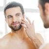 Ein Mann steht vor einem Spiegel für die Männer Gesichtspflege