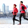 Ein Mann und eine Frau joggen vor einer winterlichen Stadt