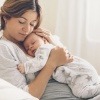 Eine Frau hält ihr Baby und denkt über ein Mommy Makeover nach