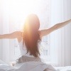 Eine Frau streckt sich im Bett nach dem Aufwachen