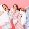 Drei junge Frauen mit Polster und Pyjama
