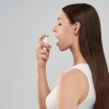 Frau benutzt Mundspray gegen Viren und Bakterien