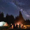 Menschen mit Zelt und Lagerfeuer am Abend mit Neumond im August