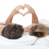 Ein Paar liegt im Bett und formt ein Herz mit den Händen