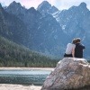 Ein Paar sitzt auf einem Felsen am See und kommuniziert