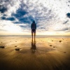 Eine Person steht am Strand unter einem dunklen Wolkenhimmel in einer besonderen Atmosphäre