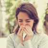 Frau zur Pollensaison im Frühling niest in ein Taschentuch