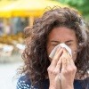 Frau niest in ein Taschentuch wegen Heuschnupfen