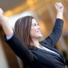 Eine Frau in einem Businessoutfit reckt triumphierend die Arme in die Luft und wirkt glücklich. Es scheint, als wüsste sie genau, wie sie ihr Potential entwickeln und nutzen kann.