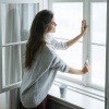 Eine Frau öffnet ein Fenster um richtig zu lüften