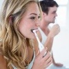 Ein junges Paar putzt sich die Zähne.