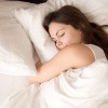 Eine Frau schläft entspannt in ihrem Bett.