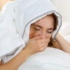 Eine Frau unter einer Decke gehnt und hat offensichtlich Schlafprobleme