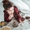 Eine Frau liegt im Bett, trinkt Wein, raucht und will schlechte Gewohnheiten loswerden.