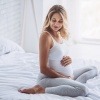 Eine schwangere Frau sitzt im Bett