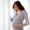 Eine schwangere Frau steht vor dem Fenster
