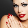 Eine Frau blickt verführerisch, hat rote Lippen und im selben Farbton die Fingernägel lackiert. Es handelt sich um eine Großaufnahme ihres Gesichtes.