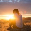 Eine Frau sitzt auf einem Berg im Sonnenuntergang und sucht den Sinn des Lebens