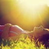 Eine Frau liegt im Gras bei Sonnenschein