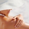 Eine Frau gibt Sonnenschutz auf ihre Haut