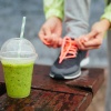 Jemand bindet ein Schuhband eines Sportschuhs, ein Smoothie ist im Vordergrund