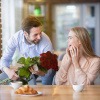 Mann schenkt einer Frau rote Rosen als Zeichen der Liebe