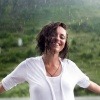 Frau mit starkem Immunsystem steht glücklich im Regen