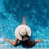 Frau mit Hut am Rand des Pools