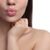 Eine Frau formt mit ihren Lippen einen Kussmund