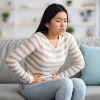 Frau mit Magenschmerzen durch Verstopfung am Sofa