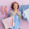 Wäsche waschen im Urlaub ohne Waschmaschine - lächelnde Frau vor Wäscheleinen mit trocknender Kleidung.