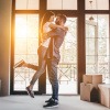 Wann zusammenziehen - glückliches Paar umarmt sich während des Kisten auspackens in der gemeinsamen neuen Wohnung. 