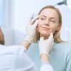 Ein Arzt erklärt einer Frau was ist Lifing und hält ihr Gesicht