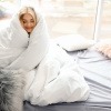 Welche Bettwäsche für Winter - Frau eingekuschelt in warmer Bettdecke.