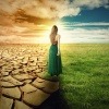 Welt verändern - eine Frau auf der Grenze zwischen einer ausgetrockneten Wüstenlandschaft und einer üppigen grünen Wiese.