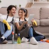 Wohnung putzen Checkliste - junges Paar macht eine Pause während des Putzens.