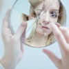 Eine Frau betrachtet sich in einem zerbrochenen Spiegel