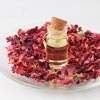 Eine Rose, ätherisches Öl und Rosenblätter liegen auf einem Teller